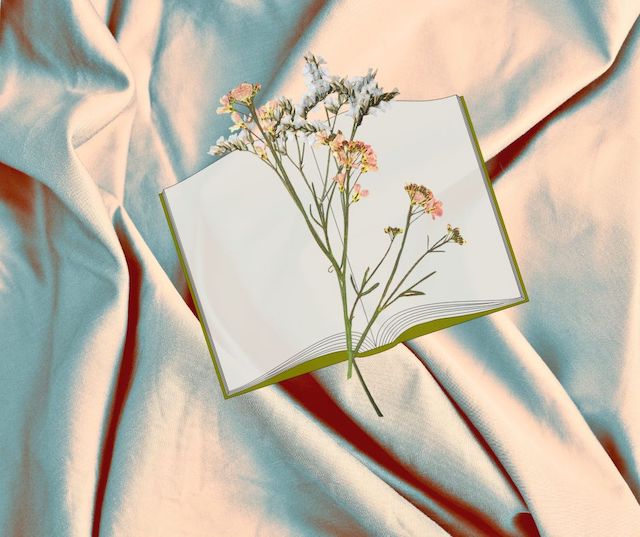 flowers and open book on top of a bedsheet